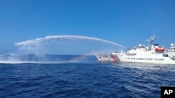 资料照:菲律宾海警提供的照片显示,在有争议的南中国海斯卡伯勒浅滩(Scarborough shoal ),中国称黄岩岛,一艘中国海警船(右)在向菲律宾渔业和水产资源局的一艘船只使用水炮。(2023年12月9日)