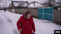 一位妇女冒雪走在乌克兰新科扎恰的街头。(2023年2月14日,美国之音博夏特拍摄)