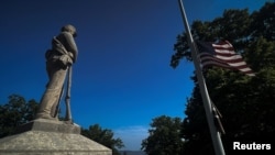 资料照:纽约哈德逊河畔橡树山公墓里一座美国内战联邦军士兵塑像旁飘扬着降半旗的美国国旗。(2023年5月29日)