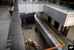 北京一家商场里的工人在工作,同时一个工人在看手机。(2023年4月27日)