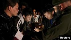 一名中国人正在给一群渡过美墨边境的格兰德河进入美国德克萨斯州的中国人当翻译，向美国边境巡逻人员报到登记，以便进入移民程序。（资料照片：2023年3月23日）