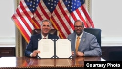 美国国会众议院议长凯文·麦卡锡(左)拿着他已签字的《美台21世纪贸易倡议首批协定实施法》与众议院筹款委员会主席杰森·史密斯众议员合影。(众议员杰森··史密斯办公室提供)