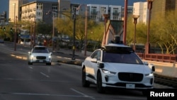 资料照片:两辆自动驾驶汽车在美国亚利桑那州凤凰城的中央大道上行驶。(2024年3月18日)