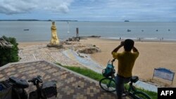 资料照:一名男子在中国厦门用一副望远镜隔海遥望台湾金门岛。(2022年8月3日)