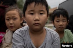 几名来自中国的儿童和他们的家人渡过美墨边境的格兰德河走出美国德克萨斯州的丛林,他们为了进入美国移民程序找到了美国执法人员。(2023年4月5日)