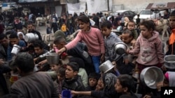 2023年12月21日,巴勒斯坦人在加沙地带拉法排队领取免费餐食。(美联社照片)