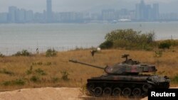资料照:台湾金门岛沙滩上停放着一辆台湾退役军用坦克与海峡对面的中国福建省厦门市。(2023年12月20日)