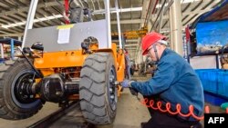 中国山东省青州市的一个铲车工厂的工人在装配铲车。(2023年10月18日)