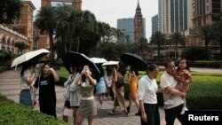 资料照片: 2023年4月30日中国澳门劳动节假期期间,游客在由金沙中国运营的澳门伦敦人赌场度假村的大本钟复制品前拍照