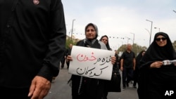 2024年8月25日,在纪念先知穆罕默德的孙子伊玛目·侯赛因在公元680年被杀后40天哀悼期结束的仪式上,一名哀悼者举着一块标语牌,上面写着:“加沙浸泡在儿童的鲜血中”。(美联社照片)