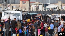 被驱离的巴勒斯坦人在加沙拉法城一个临时营帐前排队购水。(2024年5月17日)