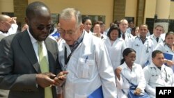 资料照片:肯尼亚基苏木省省长安扬·尼永戈教授(左)与参加位于内罗毕肯尼亚政府学院项目的100名古巴医生之一交谈。(2018年6月11日)