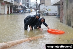 中国湖南省长沙市暴雨中的街道,工人冒雨疏通下水道。(2024年6月24日)