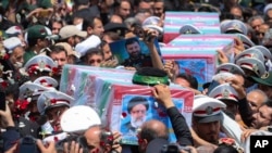 2024年5月23日，在伊朗马什哈德市举行的葬礼上，人们抬着覆盖着国旗的莱希总统及其同机人员的灵柩。（美联社照片）