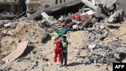 2024年6月21日,以色列轰炸汗尤尼斯后,一名巴勒斯坦儿童手拿从被毁建筑物的废墟中找回的毛绒熊。(法新社照片)