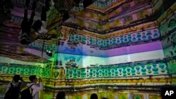 2021年9月26日在北京举办的每年一度的国际中国高科技博览会上,参观者戴着口罩一边观看一边收听介绍用高科技仿真技术模拟被烧毁的圆明园前美轮美奂的景色。