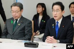 日本首相岸田文雄在星期五一场政策会议上讲话,日本国家公安委员长谷公一(左)坐在他身旁。(2023年4月28日)