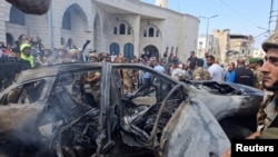 据两名巴勒斯坦消息人士称,2024年8月21日的黎巴嫩,在以色列袭击南部港口城市西顿郊区后,人们和黎巴嫩军人站在一辆被烧毁的汽车附近。(路透社照片)