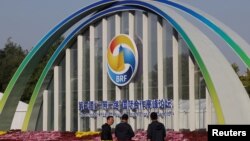 2023年10月16日,第三届“一带一路”论坛在中国北京举行,人们站在中国国家会议中心的标牌旁。 (路透社图片)