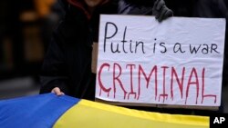 На міжнародному рівні Путіна вже визнано обвинуваченим воєнним злочинцем відповідно до ордеру на арешт МКС за звинуваченнями, що Путін особисто причетний до депортації тисяч дітей з України. Фото: AP, архівне фото із протесту у Белграді, Сербія, фото за 26 лютого 2022 року