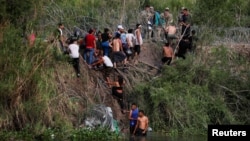 大批来自中美洲的移民渡过美墨边境的格兰德河进入美国德克萨斯州,向美国边境巡逻人员报到。(2023年5月10日)