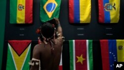 一名土著男子在巴西贝伦举行的亚马逊合作会议上观看巴西国旗。（2023年8月6日）