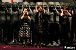 香港苏富比拍卖中国艺术家岳敏君的作品前观众与他的作品合影。(2011年3月31日)