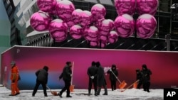 北京一家已经为圣诞节装饰起来的商场外工人们在清除积雪。(2023年12月14日)