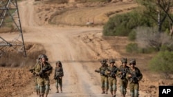 资料照片:以色列军人在以色列南部的加沙边境地区行进。(6月13日)