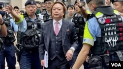 香港民主派初選47人案其一名獲判無罪的被告,大律師劉偉聰5月30日手持厚達337頁的判辭離開西九龍裁判法院時,被大批軍裝警員包圍。(美國之音)