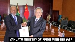 瓦努阿图总理办公室2024年7月2日发布图片显示,瓦努阿图总理萨尔瓦伊(左)与中国全国政协副主席胡春华在新总统府的正式移交给瓦努阿图政府的仪式上握手。