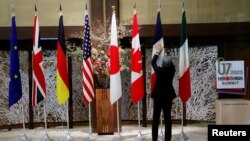 资料照:一名男子在日本东京举行七国集团外交部长会议期间整理成员的旗帜。(2023年11月8日)