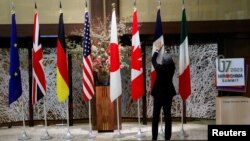 资料照:一名男子在日本东京举行七国集团外交部长会议期间整理成员的旗帜。(2023年11月8日)