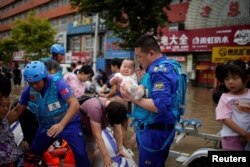 由志愿者组成的中国民间救援队蓝天救援队成员在河南郑州对洪灾灾民实行救援。(2021年7月22日)