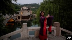一名穿着传统服装的妇女在北京热门旅游景点古北水镇的古村落里自拍。中国拟扩大免签吸引更多外籍观光客。(美联社:2020年6月9日)