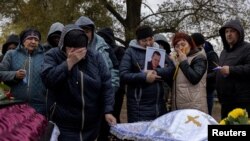 2023年10月9日,乌克兰哈尔科夫附近赫罗扎村的村庄公墓,家人和亲戚哀悼在俄罗斯持续入侵期间丧生的亲人。(路透社图片)