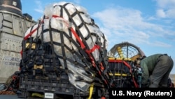 美国海军发布的照片显示一名士兵准备把从南卡罗莱纳州沿海海域打捞出来的被击落的中国气球残骸运往位于弗吉尼亚的美国联邦调查局。(2023年2月10日)