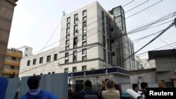 中国北京长峰医院2023年4月18日发生致命火灾的第二天,人们在楼外观看火灾造成的破坏。(路透社)