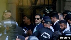 资料照片:2023年5月12日,安全人员在巴基斯坦伊斯兰堡护送前总理伊姆兰·汗(中)在伊斯兰堡高等法院出庭。(路透社照片)