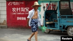 资料照:2015年7月20日中国浙江桐庐农民走过淘宝广告墙