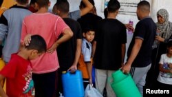 资料照片:在加沙地带南部汗尤尼斯,一些巴勒斯坦人在饮用水短缺的情况下聚集取水。(2023年10月15日)