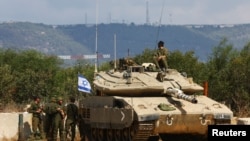 资料照片:以色列军人和一辆坦克在以色列北部与黎巴嫩的边境地区。(2023年10月16日)