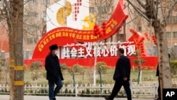 资料照:新疆和田居民走过街头竖立的社会主义核心价值观的宣传牌。(2021年3月22日)