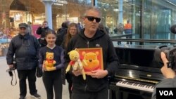 1月26日,在伦敦圣潘克拉斯国际车站,钢琴家卡瓦纳展示维尼熊玩偶和画像 (美国之音/李伯安)