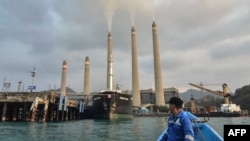 Seorang nelayan sedang memperhatikan PLTU Suralaya di Cilegon, Provinsi Banten, 31 Oktober 2023. (Ronald SIAGIAN / AFP)