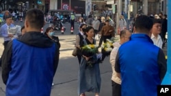 在中国前总理李克强的安徽合肥故居前,身穿蓝色马甲的保安人员注视着排队为李克强鲜花的民众队伍。(2023年11月2日)