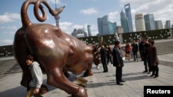 资料照:人们在上海外滩金融牛旁拍照。(2011年11月15日)