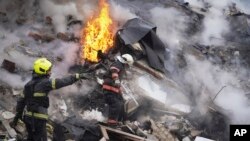 2024年1月23日,乌克兰哈尔科夫的救援人员在被俄罗斯火箭弹损坏的建筑物现场工作。(美联社照片)