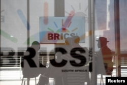 资料照:在南非约翰内斯堡参加金砖国家领导人会议的南非代表团成员坐在玻璃幕墙内。(2023年8月23日)