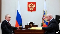 资料照片:2023年2月14日,俄罗斯总统普京(左)在俄罗斯莫斯科听取70岁的米罗诺夫讲话。(美联社照片)